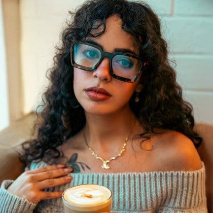 A girl with River Amber Tortoise is enjoying coffee.