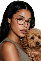 Woman wearing coco brown glasses holding a small brown dog
